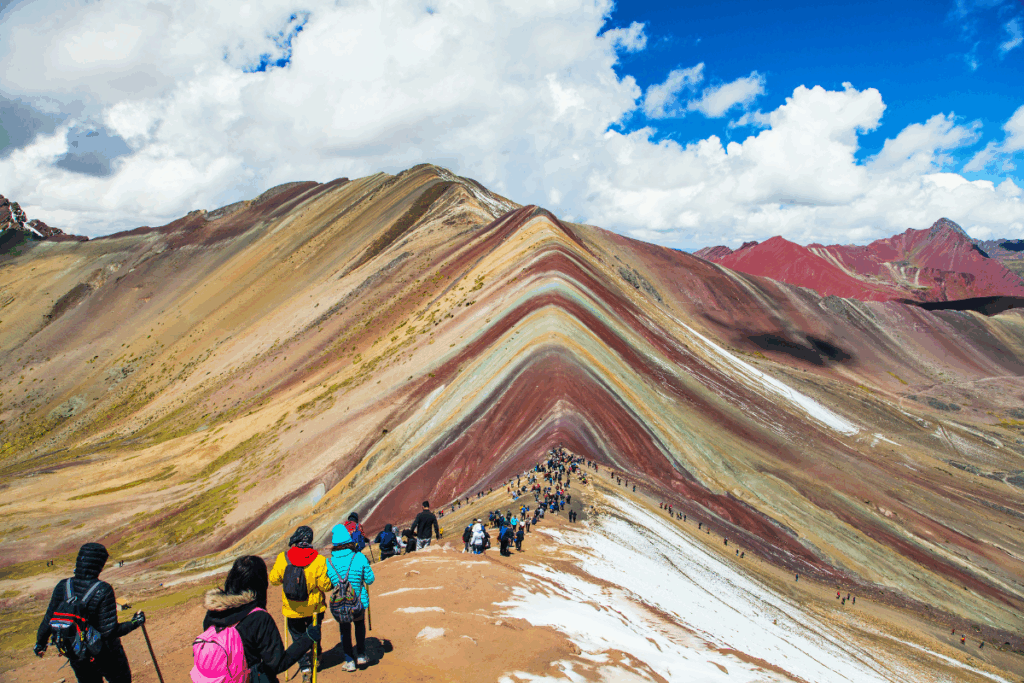 Turistas caminando entre montañas de 7 colore en los Andes peruanos